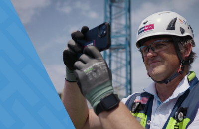 Suffolk worker in hard hat and gloves using a HammerTech on a mobile device for construction site safety