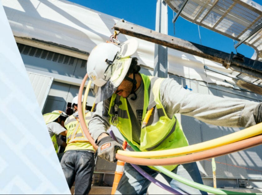 Image of electricians pulling wire and tubes for commercial construction project that uses HammerTech construction safety software. Photo courtesy of Nox Group.